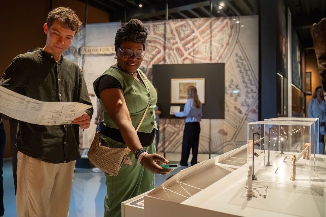 Wat zie je op deze foto: Je ziet twee bezoekers bij de tentoonstelling Amfortica. De man heeft een kaart vast en de vrouw kijkt naar de kunst. Deze foto is gemaakt door Ralf Silvius