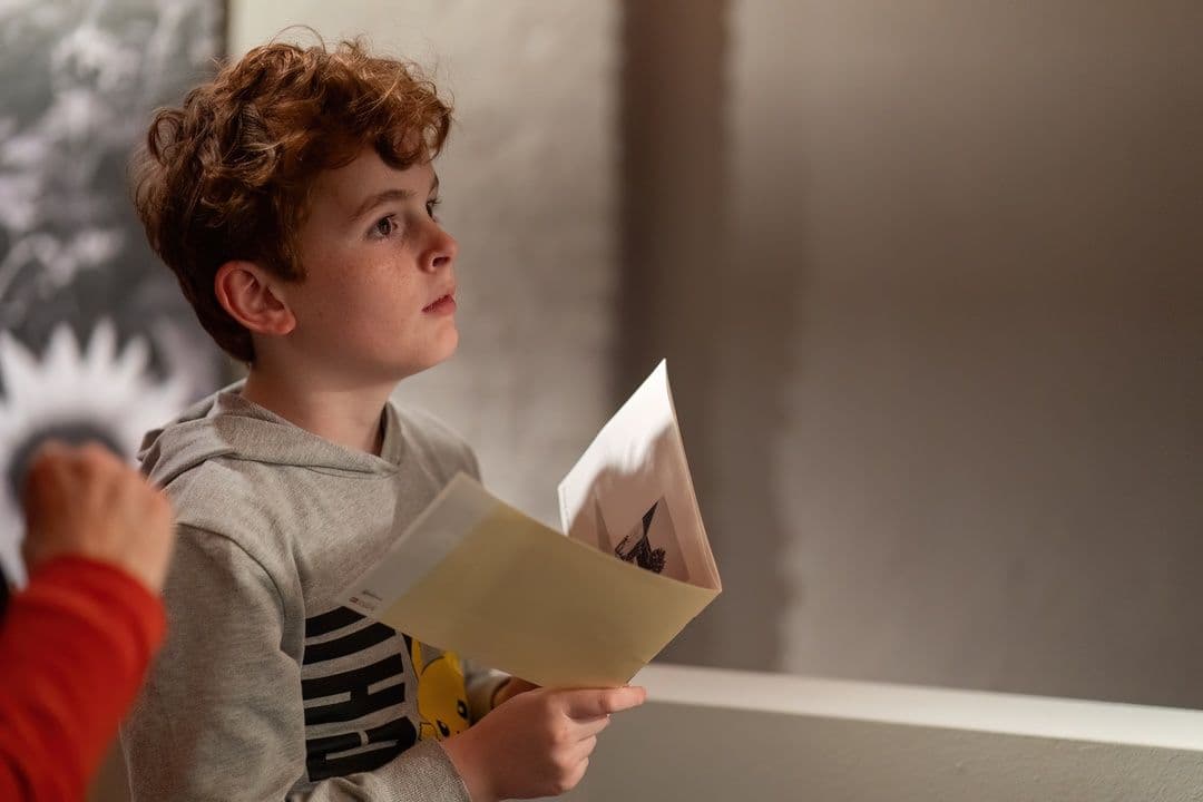 Op deze afbeelding zie je: Een kind die de tentoonstelling bezoek van A Closser Look van Carla Kogelman in het Kinderpanel en hij staart naar voren met een boekje in zijn hand. Deze foto is gemaakt door Ralf Silvius