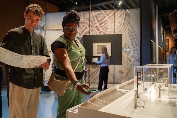 Wat zie je op deze foto: Je ziet twee bezoekers bij de tentoonstelling Amfortica. De man heeft een kaart vast en de vrouw kijkt naar de kunst. Deze foto is gemaakt door Ralf Silvius